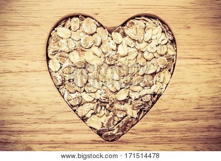 Dieting healthcare concept. Oat cereal oatmeal heart shaped on wooden surface. Healthy food for lowering cholesterol.