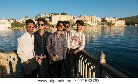 Udaipur India - January 30 2017: Group of young people at Udaipur with the famous city palace on Lake Pichola reflecting sunset light. Travel destination and tourist attraction in Rajasthan India.