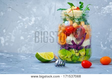 Healthy take-away lunch jar with guacamole tofu vegetables chickpeas and hummus. Love for a healthy vegan food concept