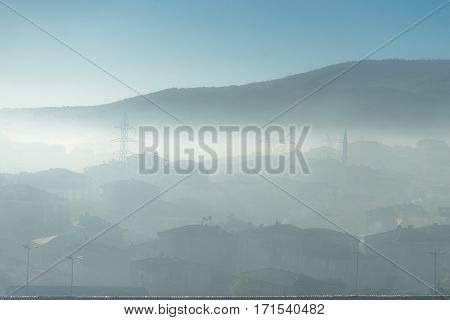 Photo taken in fogy day. Houses is under fog but you could see sun over fog. Houses is only seen as a silhouette.