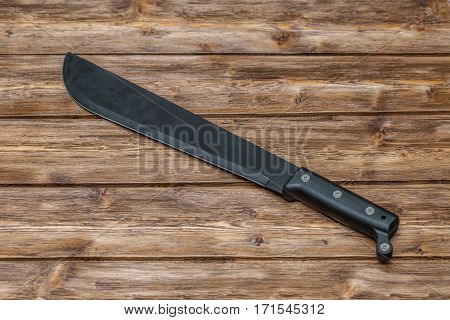 Machete for cutting grass on brown wooden background
