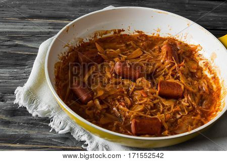 Bigus with sausages in a frying pan on a wooden background in rustic style
