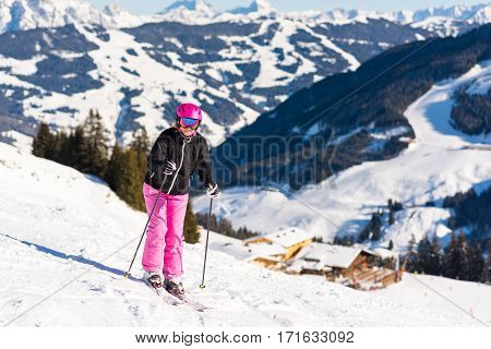 portrait of an attractive middle aged woman with skis close to a skiing hut