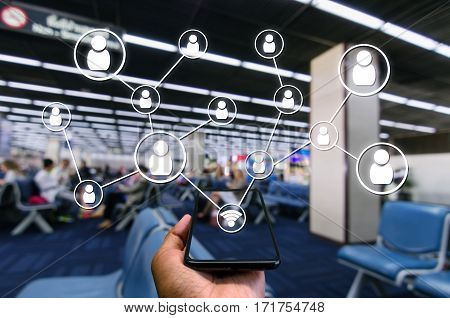 Hand using Smartphone and wifi icon social media connection concept at the airport on blurred background of passengers waiting bording at airport, color tone effect.