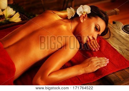 Massage of woman in spa salon. Girl on candles background in massage and skincare spa salon. Luxary interior in oriental therapy salon. Portrait of female bare back with smooth skin have relax .