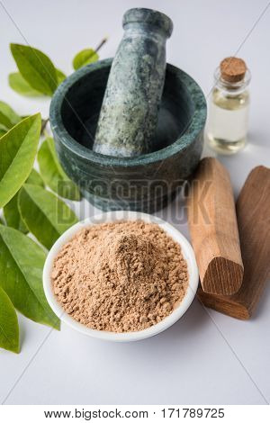Chandan or sandalwood powder with traditional mortar, sandalwood sticks, perfume or oil and green leaves. selective focus