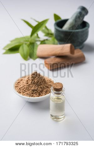 Chandan or sandalwood powder with traditional mortar, sandalwood sticks, perfume or oil and green leaves. selective focus