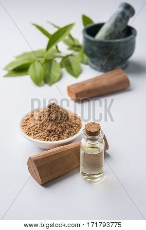 Chandan or sandalwood powder with traditional mortar, sandalwood sticks, perfume or oil and green leaves. selective focus