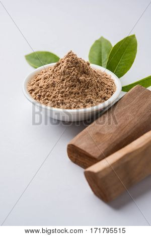 Chandan or sandalwood powder with traditional mortar, sandalwood sticks, perfume or oil and green leaves. selective focus