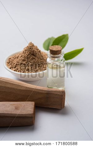 Chandan or sandalwood powder with traditional mortar, sandalwood sticks, perfume or oil and green leaves. selective focus