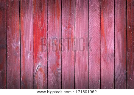 vertical planks of faded red painted worn planks on horizontal piece of fence or door