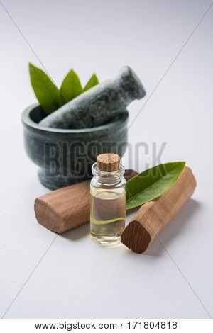 Chandan or sandalwood powder with traditional mortar, sandalwood sticks, perfume or oil and green leaves. selective focus