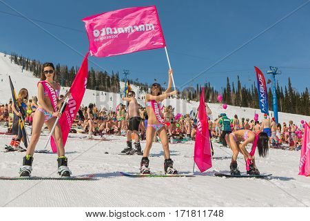 Group Of Young Happy Pretty Women On A Snowboard In Colorful Bikini With Flags.