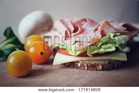 A ham and cheese sandwich on a plate with vegetables