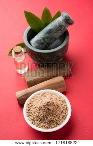 Chandan or sandalwood powder with traditional mortar, sandalwood sticks, perfume or oil and green leaves. selective focus