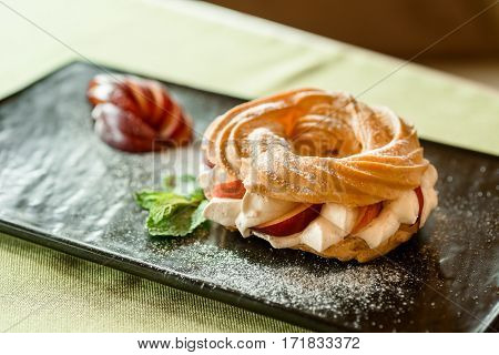 desert on breakfast, eclair donut whith apples on black plate and green tablecloth at morning