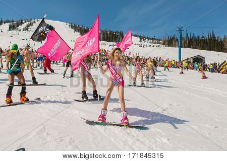 Group Of Young Happy Pretty Women On A Snowboard In Colorful Bikini With Flags.