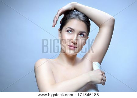 armpit axillary space attractive young caucasian woman  body care isolated  on blue background studio shot figure body applying deodorant
