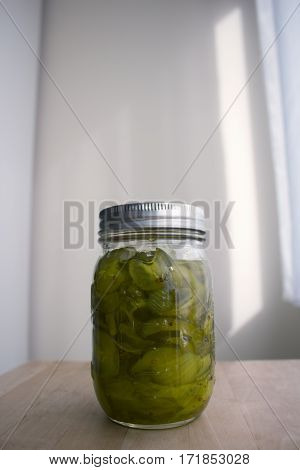 A glass jar filled with sliced, homemade pickles.
