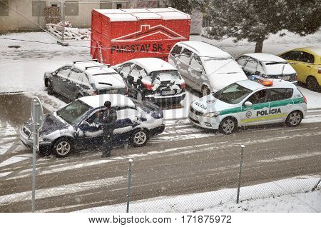 Bytca Slovakia - February 17 2017: Police traffic partol stop a car. Policeman stand outside vehicle in bad weather and talk with driver while snow falls.