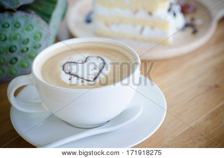 Closeup offee cup with heart shape latte art on wood table