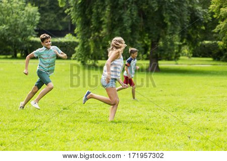 friendship, childhood, leisure and people concept - group of happy kids or friends playing catch-up game and running in summer park