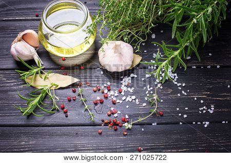 Bottle With Olive Oil With Herb And Spices Ob Black Wooden Background. Top View. Selective Focus. Pl