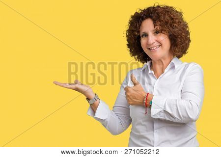 Beautiful middle ager senior businees woman over isolated background Showing palm hand and doing ok gesture with thumbs up, smiling happy and cheerful