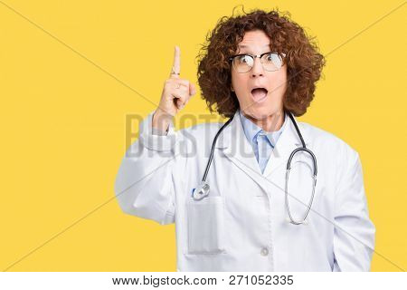 Middle ager senior doctor woman over isolated background pointing finger up with successful idea. Exited and happy. Number one.