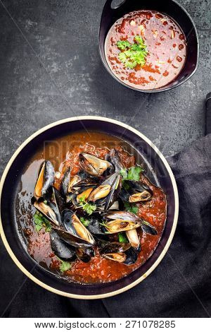 Traditional barbecue Italian blue mussel in tomato sauce with parsley and garlic in red wine sauce as top view on modern design plate 