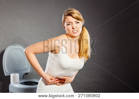 Bellyache, Constipation Or Food Poisoning. Woman Suffering From Strong Abdominal Pain, Holding Medic