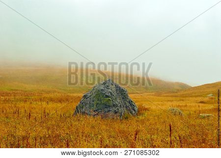 Huge Granite Boulder Lying In The Middle Of An Autumn Alpine Meadow On A Mountain Pass Sheltered By 