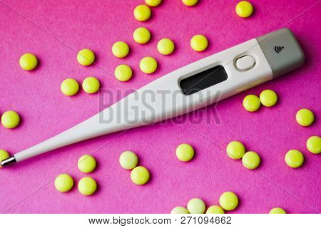 Small Medical Pharmacetic Round Pills, Vitamins, Drugs And Electronic Digital Thermometer On A Pink 