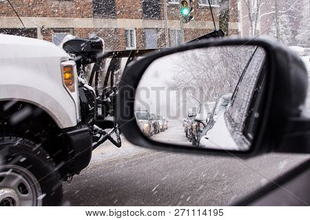 Winter Snow Storm Driving In Snow  With Traffic In Rear View Mirror And Snow Plow Driving On Street 