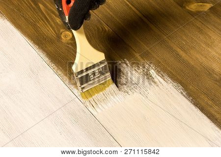 Human Hand With Brush Painting Wooden Table .
