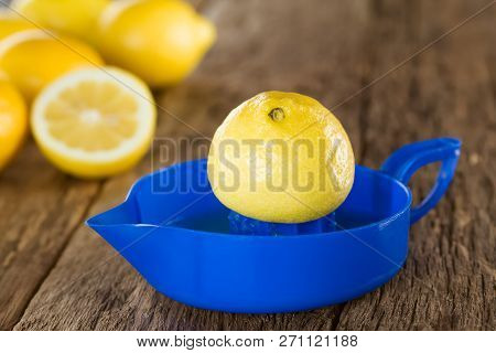 Lemon Half On Blue Lemon Or Citrus Squeezer With Lemons In The Back, Photographed On Wood (selective