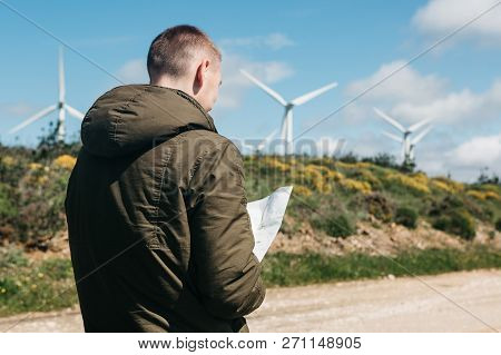 A Tourist Man Looks At The Map Of The Area For Further Travel. Unknown Terrain Or Unfamiliar Territo