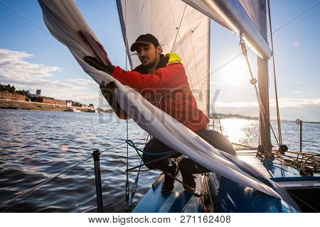 Handsome Man On Yacht Touches White Sail Called Assymetric Spinnaker, Works With Tackle In Sea At Su