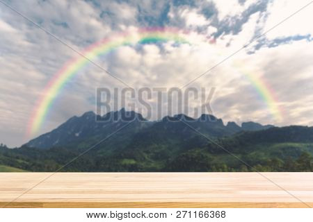 Wood Table For Display Product And Blurry Mounatin With Raindow In Background.