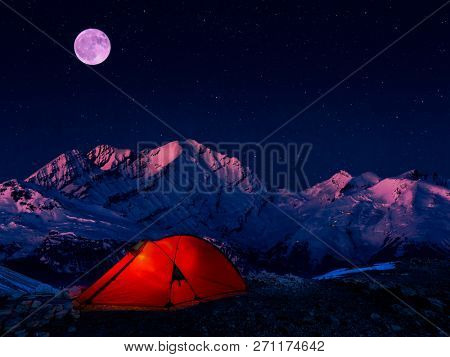 Night bivouac in Mountains, milion star hotel under night sky, red illuminated tent on pass in Alps.