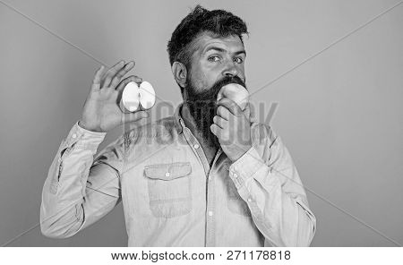 Man Bearded Eats Fruit, Holds Apple Blue Background. Half Of Apple Healthy Lifestyle. Hipster Demons