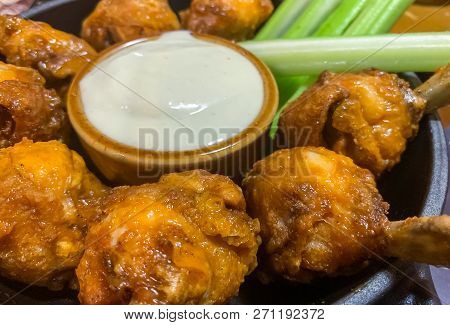 Delicoius Chicken Wings And Celery Sticks Placed In A Round Plate With A Small Bow Of White Sauce In