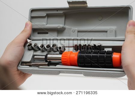 Master Holds In His Hands A Screwdriver. Screwdriver Set In Box On White Background.