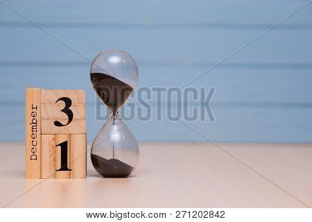 December 31St Set On Wooden Calendar And Hourglass With Blue Background.