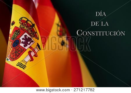 some spanish flags and the text dia de la constitucion, constitution day written in spanish, on a dark green background