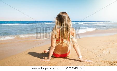 Rera View Photo Of Beautiful Young Woman In Red Bikini Relaxing On The Beach And Looking At Horizon
