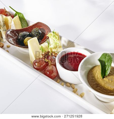 Wine Plate with Camambert, Mozzarella, Chicken Pate, Sweet Jam, Grapes, Nuts and Olive. Various Fruit, Meat and Cheese Snacks with Croutons Isolated on White Background