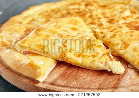 Megrelian Khachapuri Made From a Delicious Tender Dough with Melted Burnt Imeretian Cheese and Butter Close Up. Traditional Most Common Circular Hachapuri Topped with Lots of Grated Cheeses