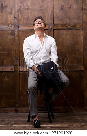 Expressive Relaxed Person Sitting In The Room Alone And Looking Delighted While Putting His Head Up 