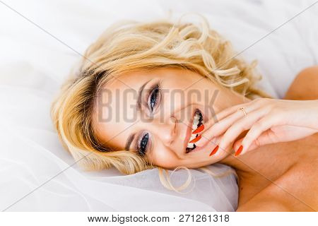 A Bride With Hairstyle And Make Up Lying On Her Dress. A Portrait Of Beautiful Girl Lying On Fatin C